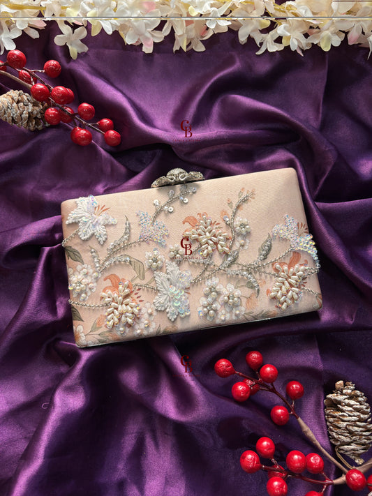 Decorative clutch bag with floral embroidery on a purple satin background with red berries and gold leaves.